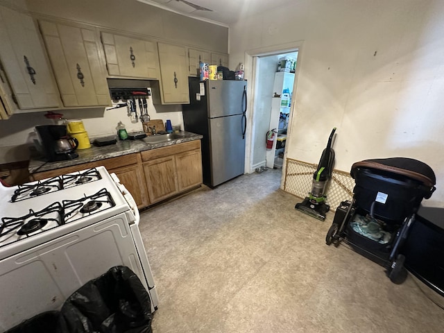 kitchen featuring stainless steel refrigerator, white range with gas cooktop, and sink