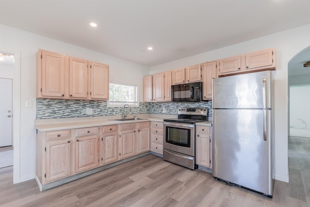 kitchen with appliances with stainless steel finishes, sink, backsplash, and light brown cabinets