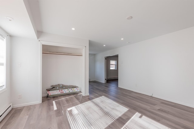 unfurnished bedroom with light hardwood / wood-style floors, a closet, and a baseboard radiator