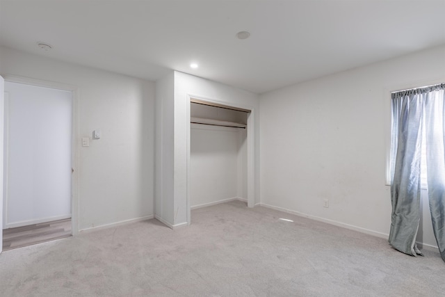 unfurnished bedroom featuring a closet and light colored carpet