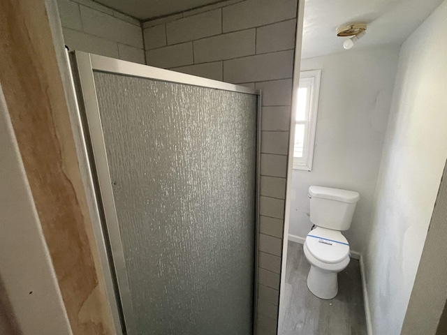 bathroom featuring a shower with door, hardwood / wood-style floors, and toilet