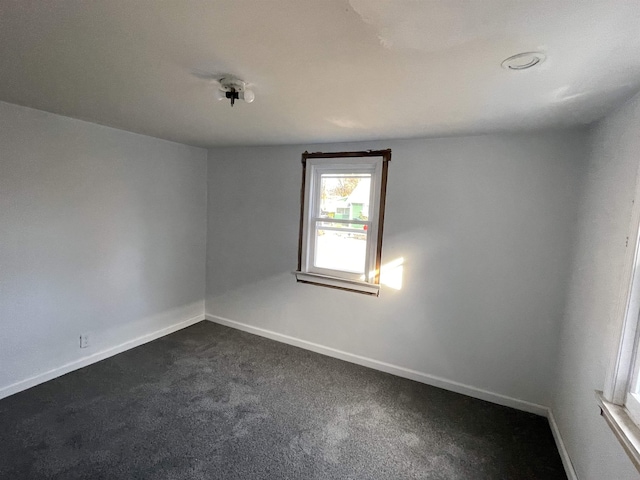 unfurnished room featuring dark colored carpet