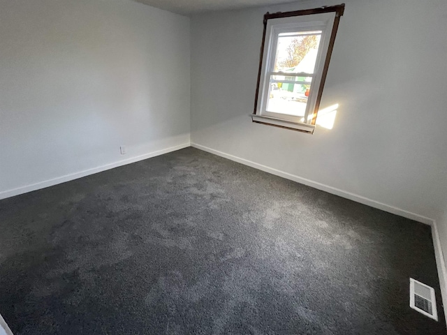 spare room featuring dark carpet