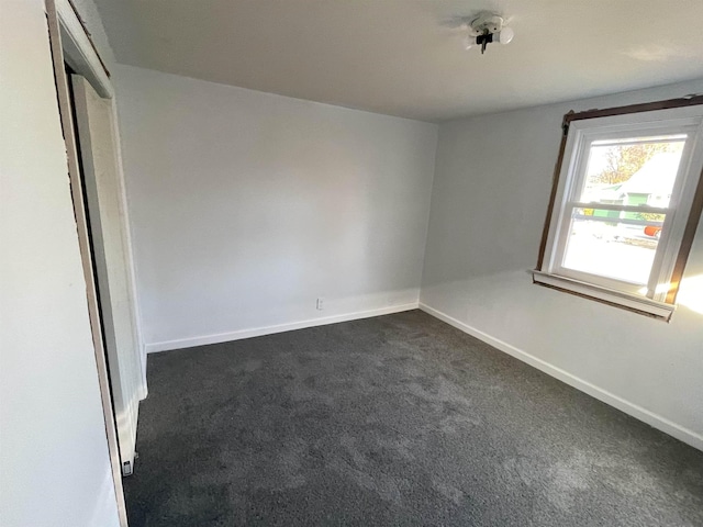 spare room featuring dark colored carpet