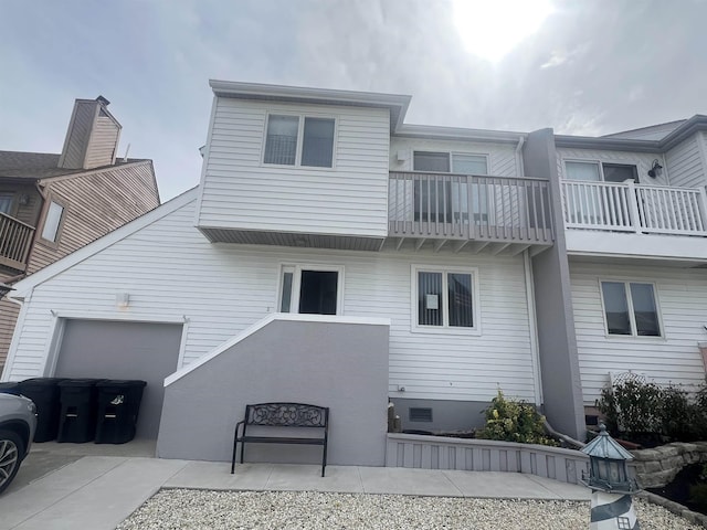 back of property with a balcony and an attached garage