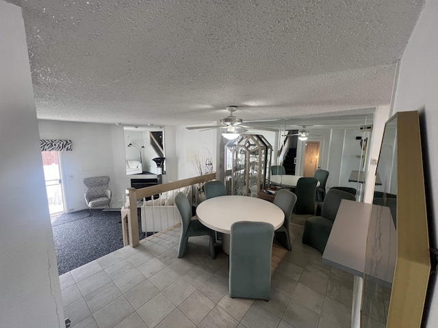 dining area featuring a textured ceiling, a ceiling fan, a fireplace, light carpet, and light tile patterned floors