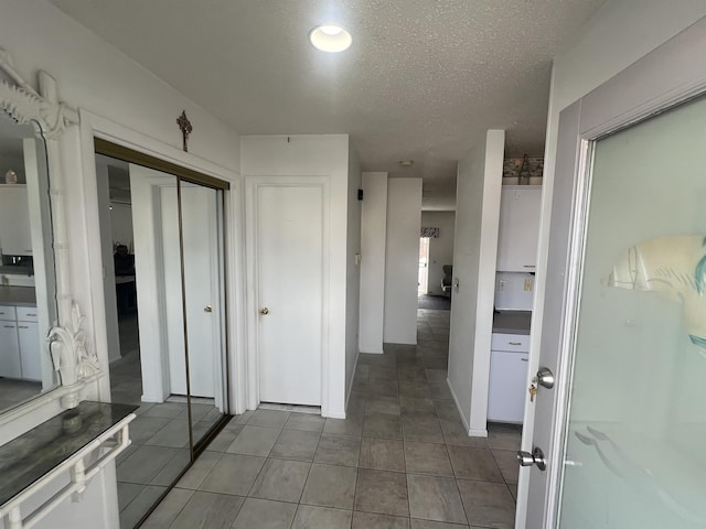 corridor with a textured ceiling and tile patterned floors