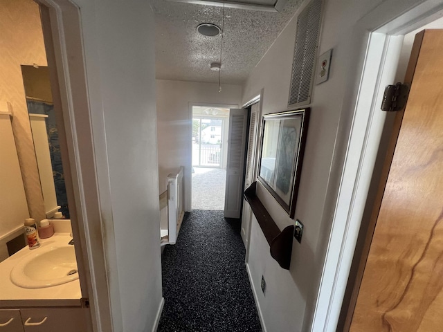hall with a textured ceiling and a sink