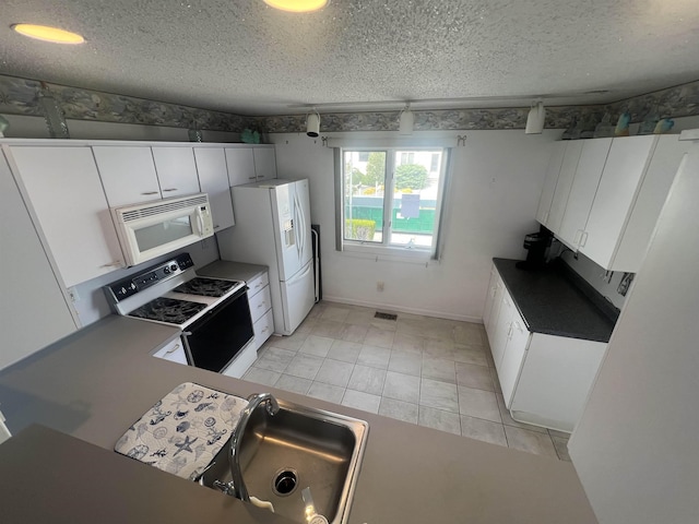 kitchen with white appliances, a textured ceiling, a sink, and white cabinets