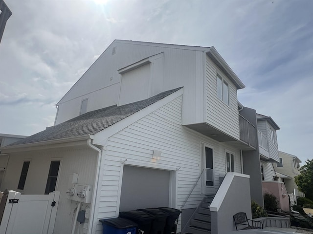 view of home's exterior with roof with shingles, a balcony, and a garage