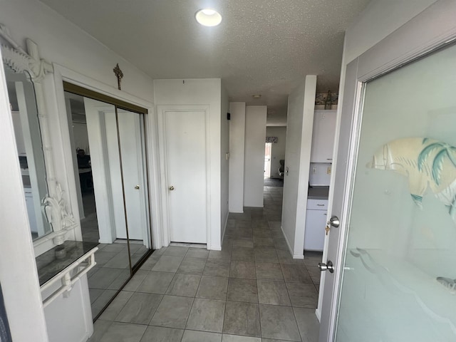 corridor with a textured ceiling and tile patterned floors