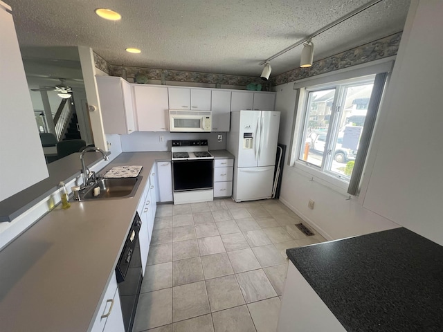 kitchen with white appliances, a sink, a textured ceiling, light tile patterned floors, and white cabinetry