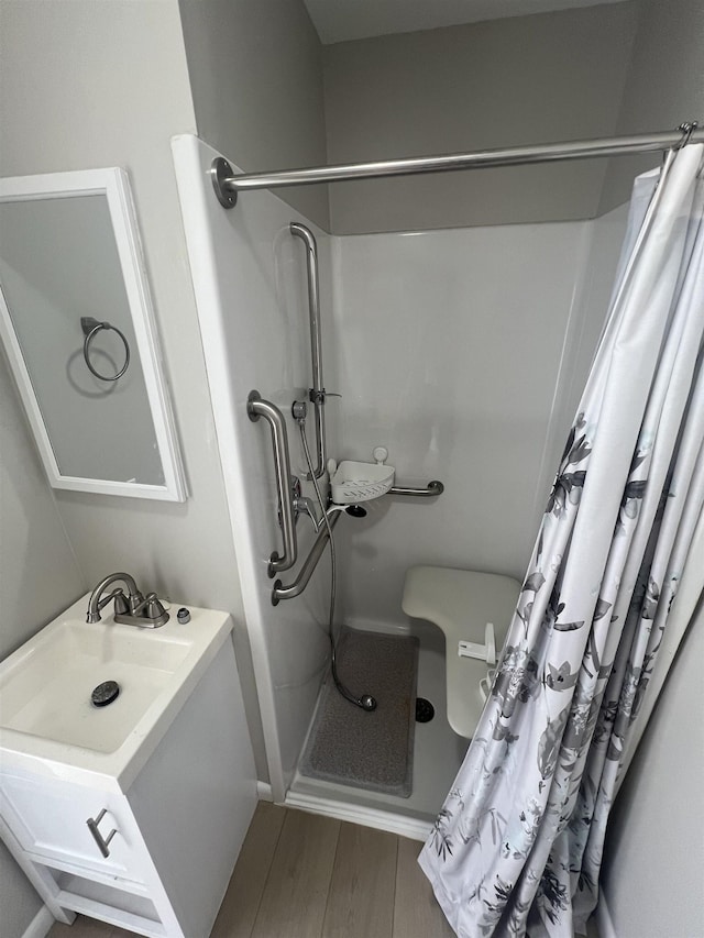 full bathroom with a shower with shower curtain, wood finished floors, and vanity