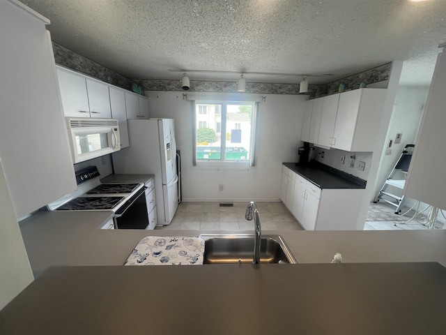 kitchen with a sink, white appliances, a textured ceiling, baseboards, and white cabinetry