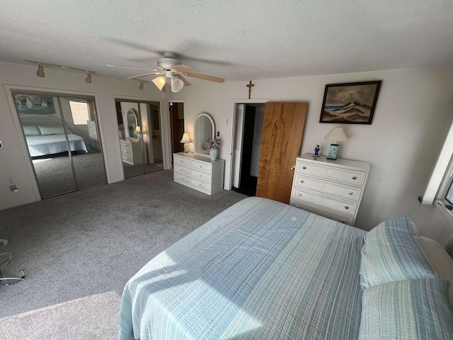 carpeted bedroom with a textured ceiling, two closets, and ceiling fan