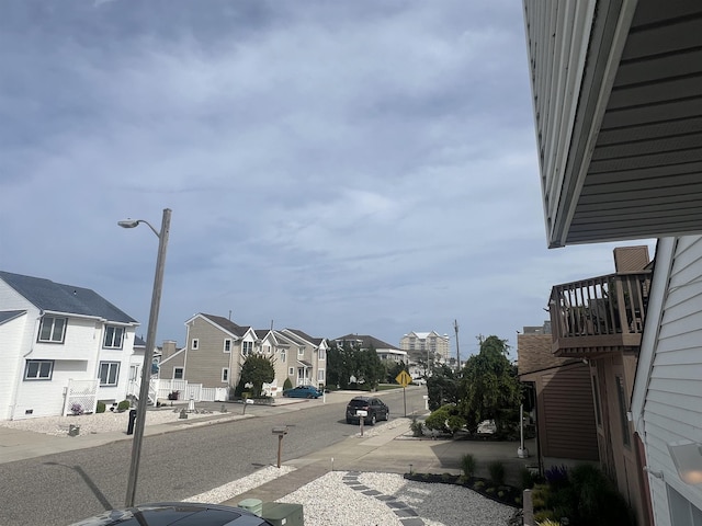 view of asphalt street featuring a residential view, traffic signs, street lighting, and sidewalks