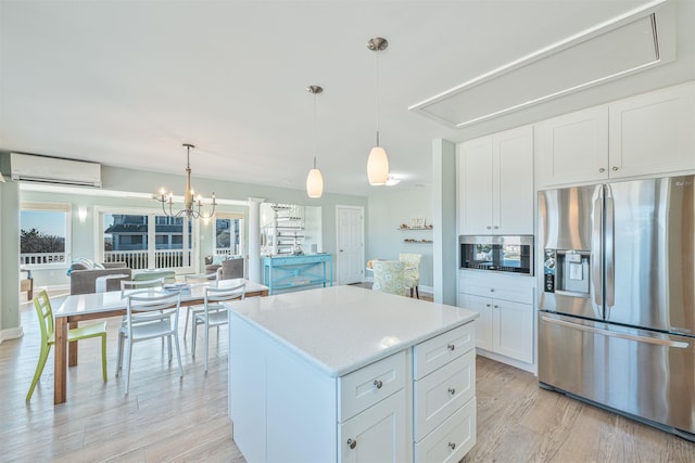 kitchen featuring a wall mounted air conditioner, a center island, white cabinets, hanging light fixtures, and appliances with stainless steel finishes