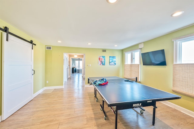 playroom featuring plenty of natural light, a barn door, and light hardwood / wood-style floors