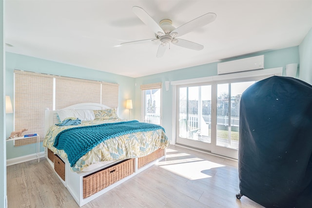 bedroom with a wall mounted air conditioner, access to outside, ceiling fan, and light hardwood / wood-style floors