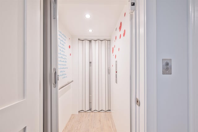 hall with elevator and light hardwood / wood-style flooring