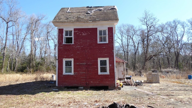 view of property exterior featuring an outbuilding and a shingled roof