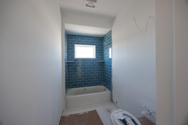 bathroom featuring tiled shower / bath and toilet