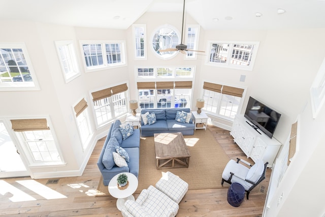 living room with ceiling fan, high vaulted ceiling, and light hardwood / wood-style flooring