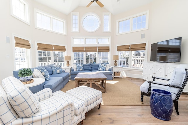 living room with high vaulted ceiling, ceiling fan, and light hardwood / wood-style flooring