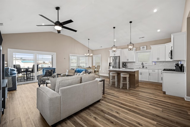 living room with ceiling fan with notable chandelier, dark wood finished floors, visible vents, and recessed lighting