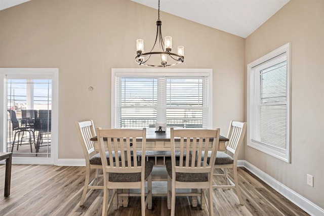 dining area featuring lofted ceiling, a notable chandelier, baseboards, and wood finished floors