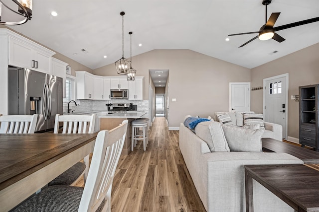 living area with vaulted ceiling, ceiling fan, light wood-type flooring, and visible vents