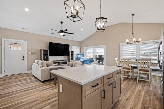 kitchen featuring ceiling fan with notable chandelier, visible vents, light wood-style floors, a center island, and pendant lighting