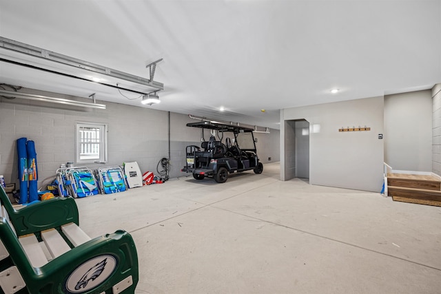 garage featuring a garage door opener and concrete block wall