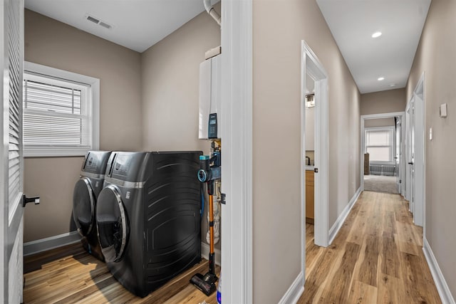 clothes washing area featuring laundry area, baseboards, visible vents, washer and clothes dryer, and light wood-type flooring