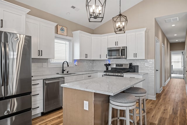 kitchen featuring stainless steel appliances, lofted ceiling, visible vents, white cabinets, and a sink