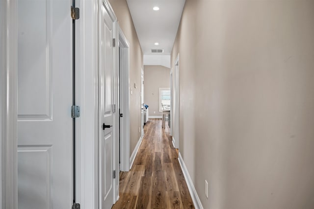 corridor featuring lofted ceiling, recessed lighting, wood finished floors, visible vents, and baseboards