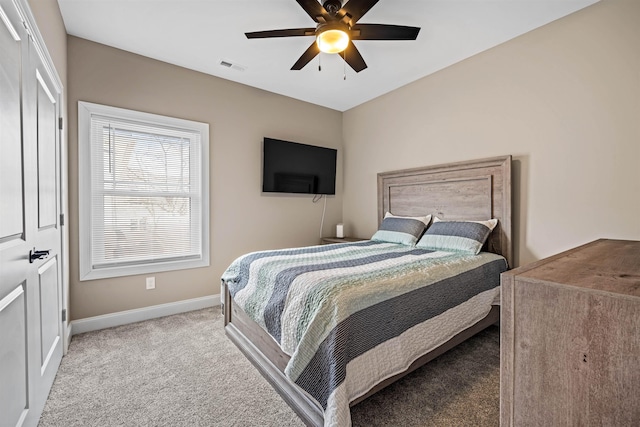 carpeted bedroom featuring a ceiling fan, visible vents, and baseboards