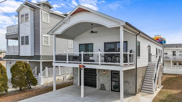 back of property featuring a garage, driveway, stairway, and ceiling fan