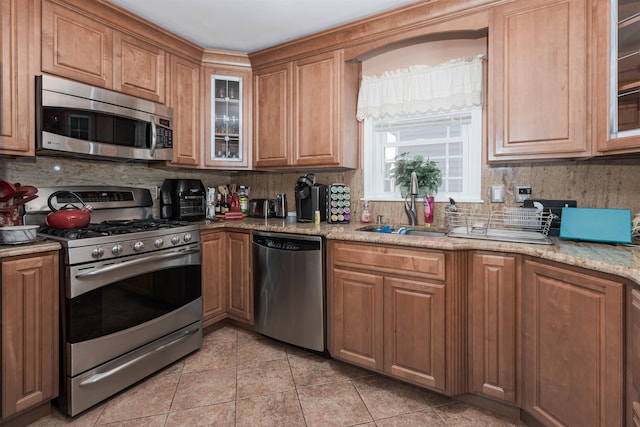 kitchen featuring decorative backsplash, appliances with stainless steel finishes, light stone counters, and light tile patterned flooring