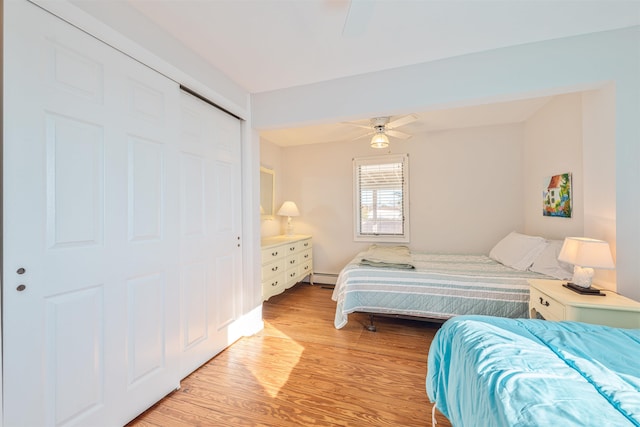 bedroom featuring a closet, baseboard heating, light hardwood / wood-style flooring, and ceiling fan