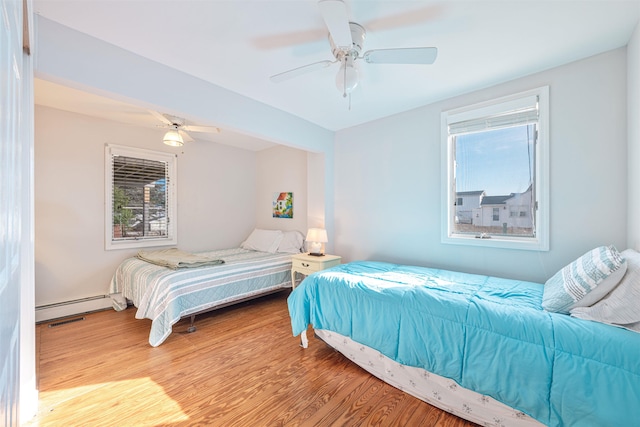 bedroom featuring baseboard heating, ceiling fan, and light wood-type flooring