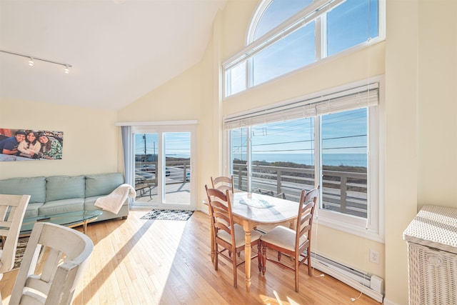 dining space featuring light hardwood / wood-style flooring, high vaulted ceiling, and rail lighting