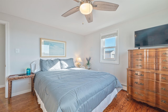 bedroom with hardwood / wood-style floors, a baseboard radiator, and ceiling fan