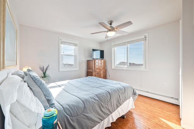 bedroom with hardwood / wood-style flooring, ceiling fan, and a baseboard heating unit