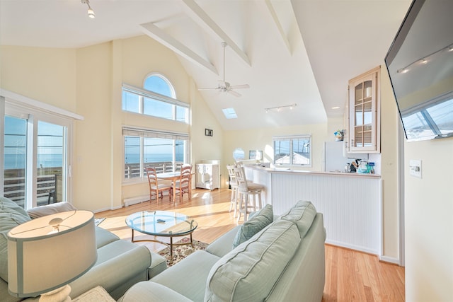 living room with a wealth of natural light, ceiling fan, high vaulted ceiling, and light hardwood / wood-style floors