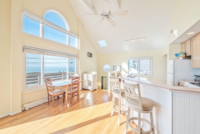 kitchen featuring ceiling fan, light brown cabinets, a water view, high vaulted ceiling, and light hardwood / wood-style flooring