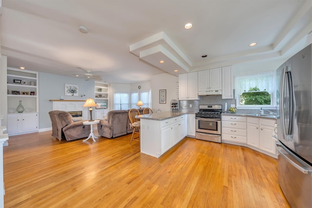 119 Stevens St, West Cape May, NJ 08204 - kitchen featuring appliances with stainless steel finishes, a peninsula, a fireplace, under cabinet range hood, and a ceiling fan