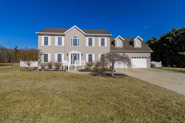 colonial house with a garage, fence, concrete driveway, and a front yard