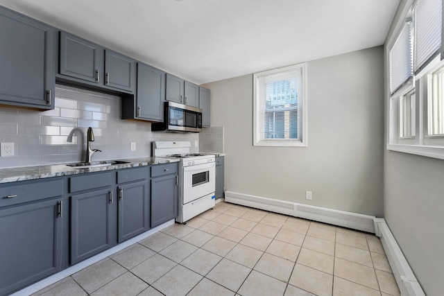 kitchen with sink, white range with gas stovetop, a baseboard heating unit, decorative backsplash, and light tile patterned floors