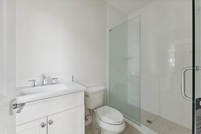 bathroom with a shower with door, vanity, and toilet